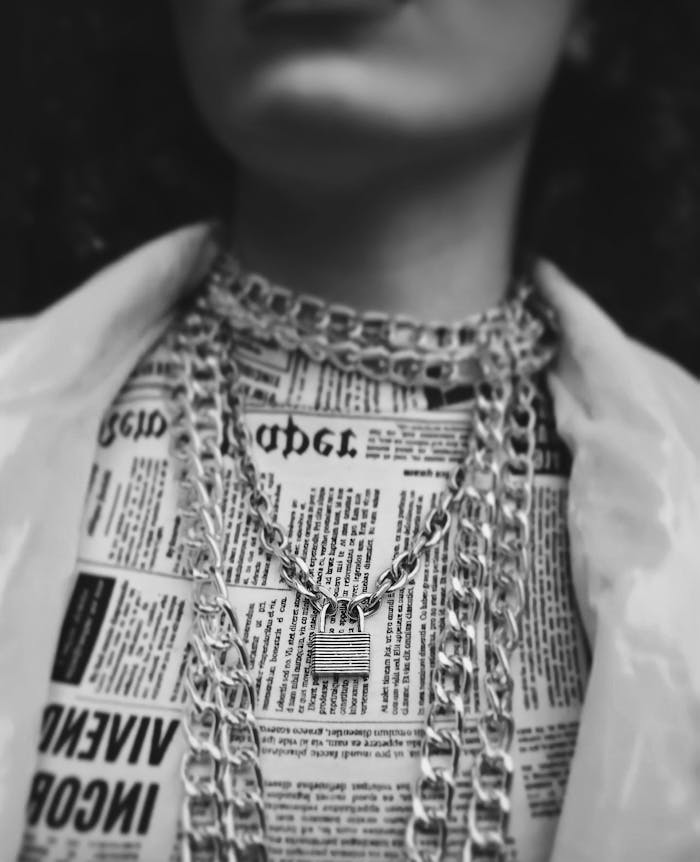 Stylish monochrome close-up of a person wearing silver chains with a padlock pendant.